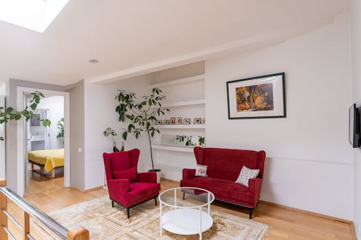 Ponuda nekretnina Bright living room featuring red armchairs, white walls, and lush plant decor.